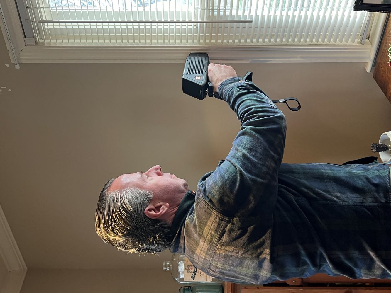 Tom Moore, the owner of Mold Testing LLC, using an XRF handheld device to detect lead paint near a window in a New Jersey home