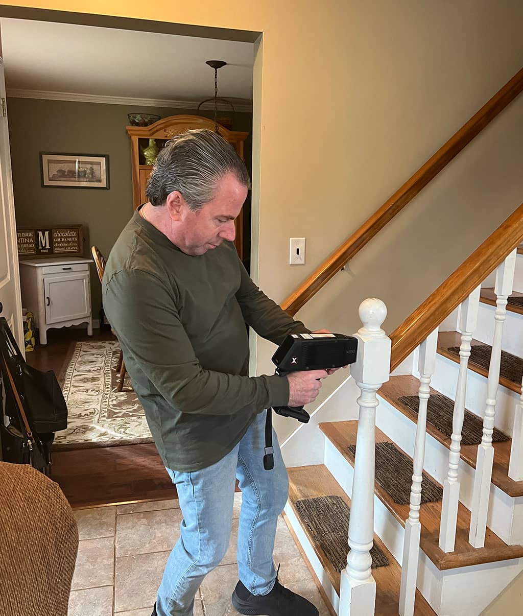 Tom Moore the owner of Mold Testing LLC using a lead testing device on a painted staircase testing for lead exposure